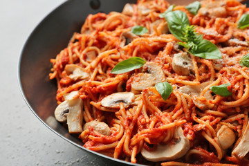 Delicious pasta with basil, mushrooms and ketchup in pan, close up view