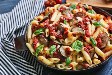 Pan with tasty macaroni and napkin on table