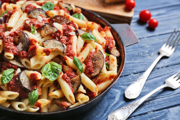 Pan with tasty macaroni and forks on wooden table