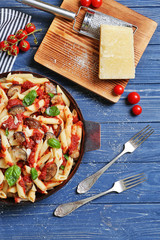 Pan with tasty macaroni, kitchen board, forks, products and grater on wooden table