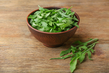 Arugula in a bowl on wooden table