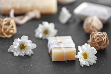 Soap and daisy flowers on grey table