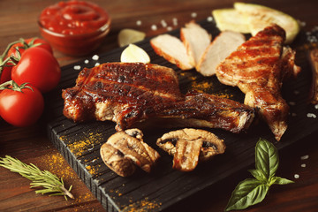 Grilled meat with vegetables on cutting board on wooden background