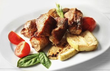 Grilled meat with vegetables on plate, closeup
