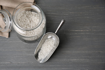 Rise in glass jar and metal scoop on wooden background