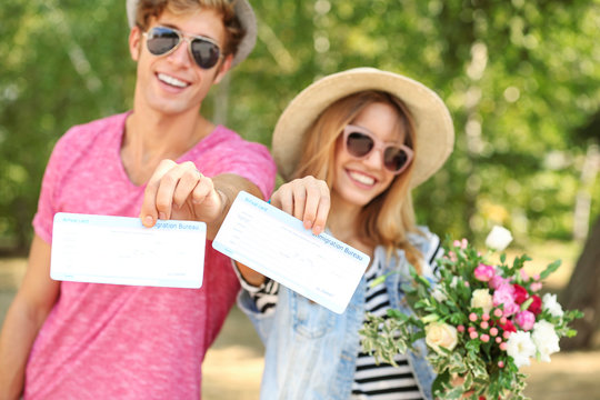 Just married couple holding tickets in park