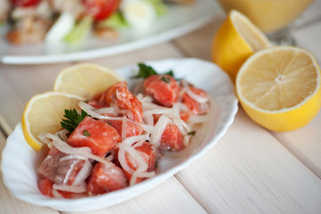 salad with onion and salmon on a white wood background