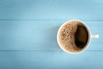 Cup of fresh coffee on blue wooden background, top view