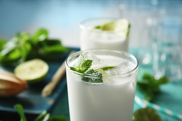 Glass of tasty milk shake with lime and mint on table, closeup