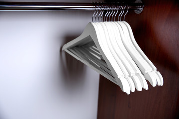 Clothes hangers in empty wardrobe, closeup