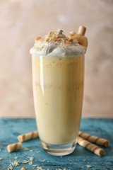 Delicious banana milkshake with sweets on blue table and beige background