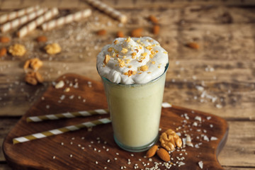 Glass of delicious nut milkshake on wooden background