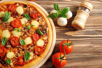 Fresh pizza with tomatoes, cheese and mushrooms on wooden background