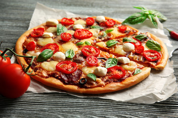 Fresh pizza with tomatoes, cheese and mushrooms on wooden background