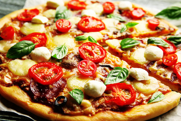 Fresh pizza with tomatoes and basil on table closeup