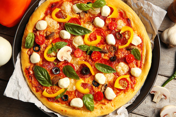 Fresh pizza with tomatoes, cheese and mushrooms on wooden table closeup