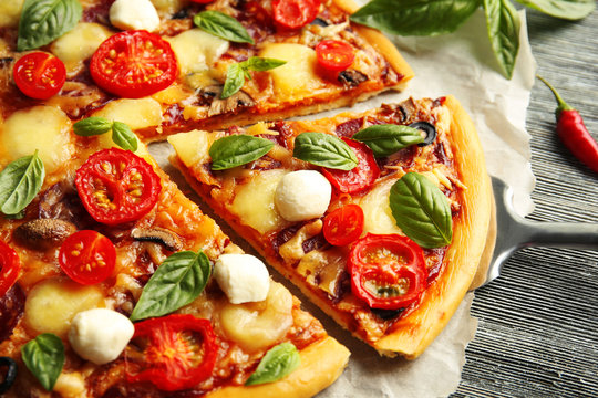 Fresh pizza with tomatoes, cheese and mushrooms on wooden table closeup