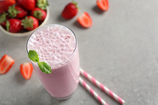 Delicious milkshake with strawberry on grey textured background