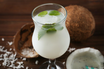 Tasty cocktail with mint and coconut on table