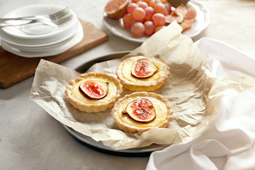Tasty cakes with figs on baking tray on table