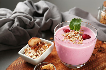 Healthy and tasty breakfast of berry milkshake with dry fruits and mint on wooden board