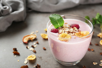 Healthy and tasty breakfast of berry milkshake with dry fruits and mint on grey table