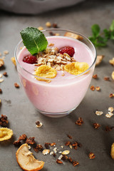 Healthy and tasty breakfast of berry milkshake with dry fruits and mint on grey table