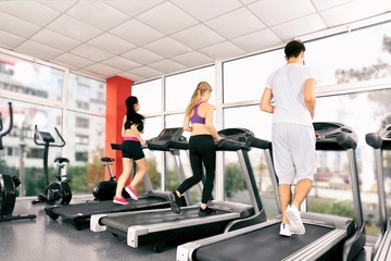 Fototapeta na wymiar Young people running on treadmills in gym
