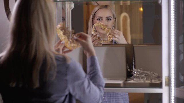 woman chooses bridal accessories in wedding boutique and wear crown with diamonds