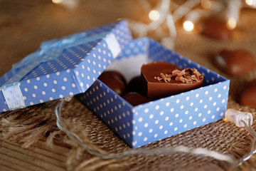 Box with chocolate hearts on sacking background