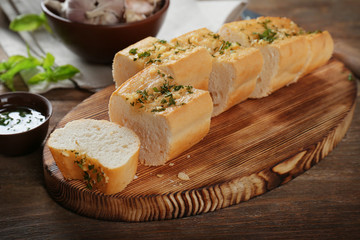 Slices of tasty bread with garlic and herbs on wooden table