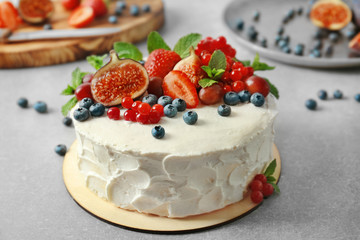 Delicious creamy cake with berries on table
