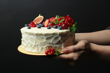 Baker hands holding delicious creamy cake closeup