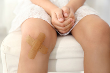 Close up view of little girl's knee with applied sticking plaster