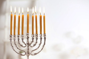 Beautiful menorah with burning candles on light blurred background. Hanukkah concept - obrazy, fototapety, plakaty