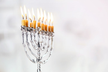 Beautiful menorah with burning candles on light blurred background. Hanukkah concept