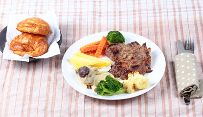 Home made ,Pork steak and mixed vegetables with croissants .