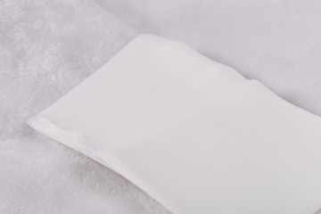Close up of a bunch of dryer sheets, sitting on a white cloth  . Dryer in the background.