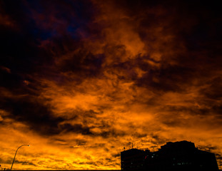 Dark silhouette of building and burning clouds in the sky at sunrise