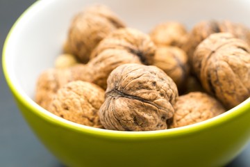 Walnuts in green ceramic bowl in close up.
