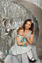 Mother and daughter are waiting for Christmas. Mom dressed fairy fairy hugs daughter. Girl holding a gift. Happy parenting and childhood. Family holidays.