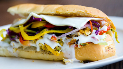 Close up of an egg sub sandwich with mayo, onions, peppers and more