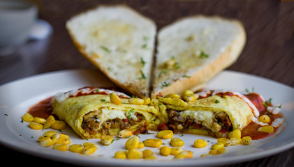 Close up shot of an Italian omelette with corn, garlic bread and more