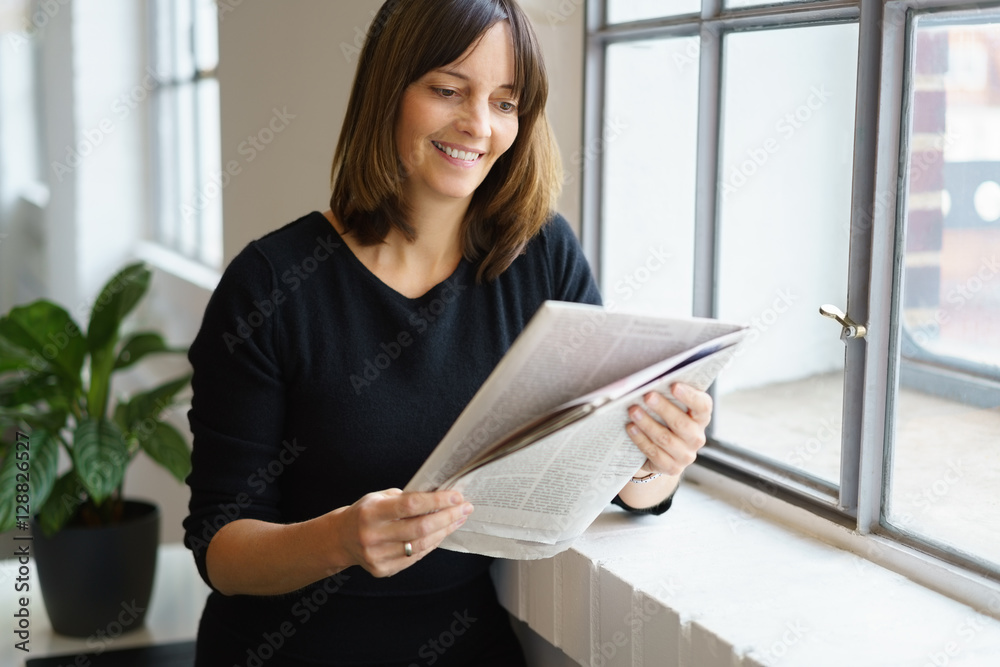 Poster frau lehnt am fenster und liest die zeitung