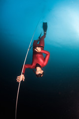 Free diver descending along the rope in the depth