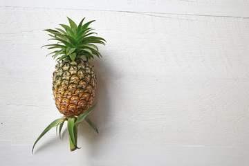 Place pineapple on a white wooden floor.