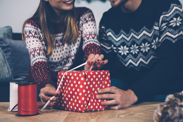 Crop couple decorating wrapped present