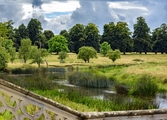 Dramatic sky over English countryside stream; overlooking wall