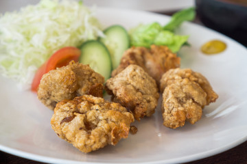 Japanese style deep fried chicken, crispy fried chicken in white plate with cabbage, cucumber and tomato for salad