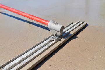 Leveling concrete with bull float, mason hands spreading poured concrete
